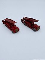 Two red cast metal ladder fire trucks side by side