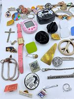 Overall view showing Tamagotchi devices, watches, pins, pendants and tie clip