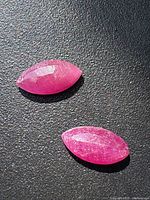 Two faceted marquise-cut rubies on black background