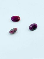 Three oval ruby gemstones on light background