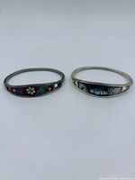 Both silver bangle bracelets side by side showing inlay panels