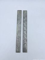 Both silver scroll weights side by side showing engravings