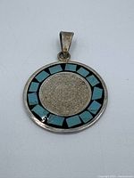 Front of pendant showing Aztec calendar coin and turquoise inlay border