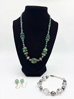 Necklace displayed on stand with bracelet and earrings in foreground