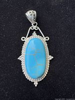 front view of pendant showing turquoise cabochon, beaded border, filigree bail