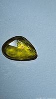 Close-up image of a natural yellow sapphire gemstone with fancy rose cut and visible inclusions.