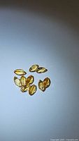 Clear photo showing a cluster of nine golden yellow marquis cut citrine gemstones on a white background, faceted and polished surface visible.