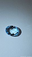 Photo of the natural sky blue topaz gemstone showing facets and color under lighting.