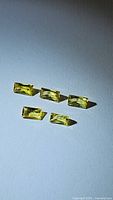 Photo of five natural bright canary yellow, rectangular baguette cut sapphires with high clarity.