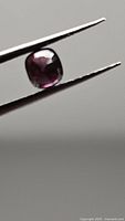 Cushion-cut spinel held by tweezers showing cut and clarity
