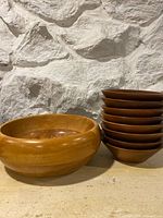 Group view of large serving bowl beside stack of eight salad dishes