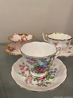 Three tea cup and saucer sets on glass shelf