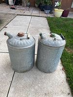 Two galvanized metal watering cans standing side by side