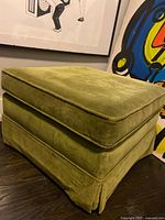 Three-quarter view of green ottoman showing skirt and fabric