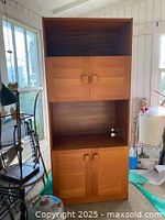 Full view of tall teak cabinet showing open top shelf, middle doors, open shelf, bottom doors