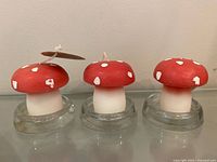 Front view of three mushroom candles on glass holders