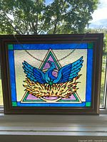 Full view of framed stained glass panel hanging in window
