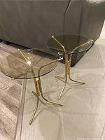 Both brass side tables angled view showing bases and glass tops