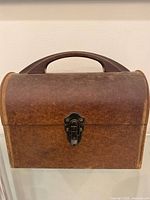 Front view showing brown lunchbox, handle, latch