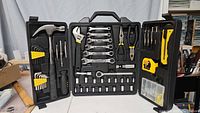 Open tool kit showing various hand tools including hammer, pliers, wrenches, screwdrivers, tape measure, utility knife, and sockets.