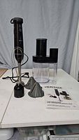 Complete set of Heritage 4-in-1 hand blender and attachments including the blender stick, whisk, chopper bowl with lid, and instruction manual.