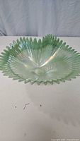 Front view of the light green art glass bowl showing its ribbed spiral design and wavy edges.