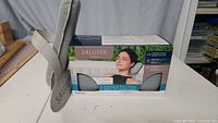 Saluspa branded packaging box for 2 padded spa headrest pillows, showing front with woman using pillow in hot tub.