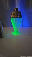 Uranium glass cocktail shaker glowing green under UV light