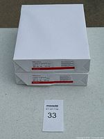 Photo of two unopened reams of white Copymart copy paper stacked on top of each other with lot number on a tag