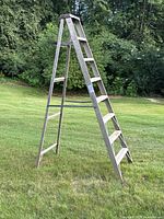 Photo showing full view of the 8 foot aluminum step ladder in A-frame position outdoors on grass.