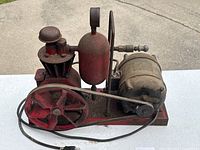 Side angle of antique air compressor showing belt and red flywheel.