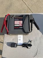 Solar ES 2500 Commercial 12V power booster pack on a gray surface with charger cable and clamps attached, all in lightly used condition and fully working.