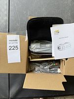 Overhead view of the open box showing the camcorder wrapped in plastic inside the carrying case, remote control, and cables all neatly organized.