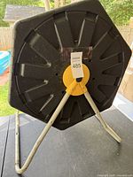 Photo of the bottom of the compost bin showing the white metal stand and the yellow central rotating handle.