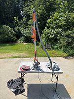 Full view of Model 1640 drywall sander with vacuum hose, sanding accessories, and carrying bags set on table outdoors.