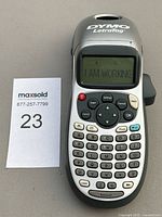 Photo of Dymo LetraTag handheld label maker showing QWERTY keyboard, display screen with test message, and control buttons.