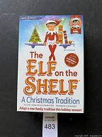 Box cover of The Elf on the Shelf Christmas tradition book showing girl elf illustration and chimney platform