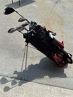 Photo showing entire golf bag with clubs inside, bag standing on sidewalk