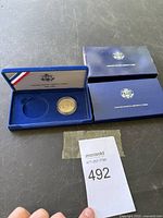 Photo showing the coin in a protective case inside a blue velvet presentation box and outer sleeve from United States Liberty Coin.