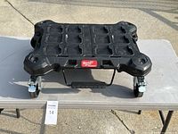 Top-down view of the Milwaukee Packout Rolling Base showing grid pattern on surface and logo badge.