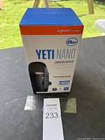 Original unopened retail box of Blue Yeti Nano USB microphone placed on a surface outdoors.