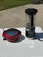 Photo showing both red Holstein Omelette Maker and Ninja Blender on a table outdoors in daylight.