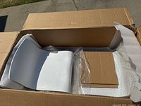 White bar stool seat visible inside open box, showing curved white plastic seating with smooth surface.