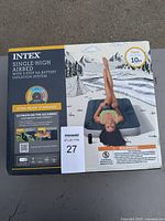 Front view of unopened Intex twin single-high airbed box showing product name, features, and outdoor camping illustration.