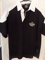 Black Guinness rugby shirt with white collar and white shoulder and sleeve panels.