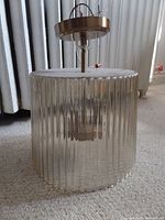 Overview of flushmount light fixture with ribbed glass shade and brass mount, on carpet floor.