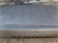 Closed large gray plastic storage tote with lid, exterior view, outdoors on pavement.