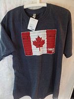 Front view of dark gray men's t-shirt with attached Blue Mountain tag and front Canadian flag graphic with 'CANADA EH!' text.