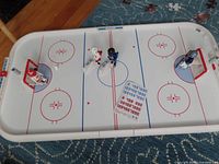 Top view of the Playmobil hockey rink with four Playmobil figures positioned on the ice surface along with player number stickers.