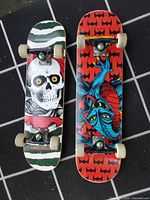 Top view of two Powell Peralta kids skateboards featuring distinct graphics - skull and blue demon